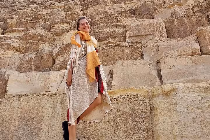 Tour guest posing by massive limestone blocks at Giza Pyramid on private Cairo tour, ancient Egypt site