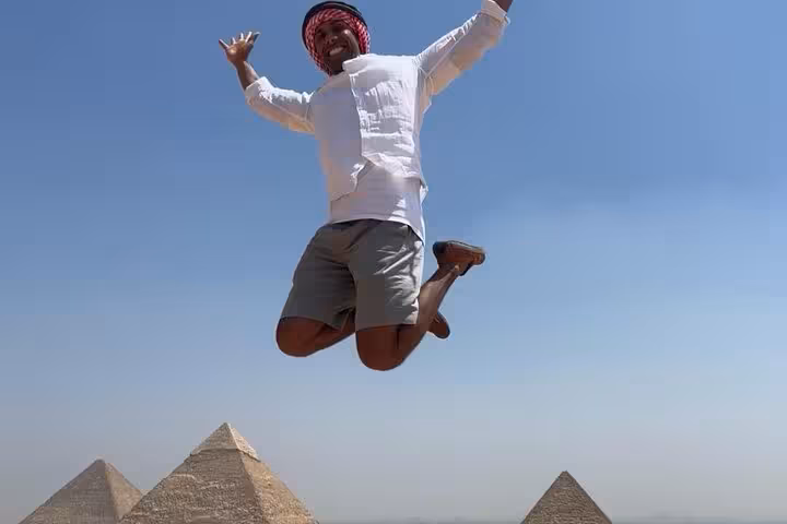 Happy traveler jumping with Giza Pyramids backdrop during a private tour to pyramids and desert viewpoints