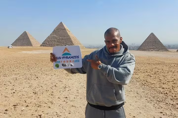 Private tour guide at Giza Pyramids holding tour sign, Great Pyramids desert backdrop near Cairo Egypt