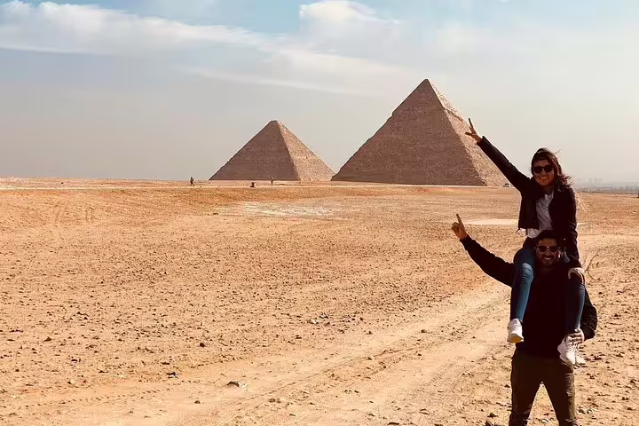Travelers posing in the Giza desert with pyramids on a private Port Said shore excursion to Giza and GEM