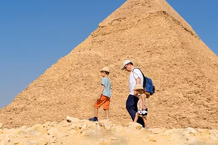 Visitors walking beside the Great Pyramid of Giza with skip-the-line entry ticket and full site access