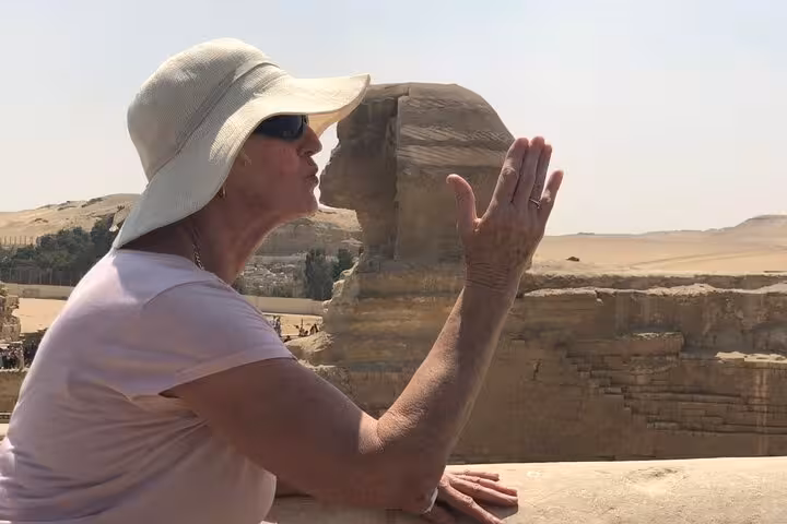 Traveler posing by the Great Sphinx of Giza on a private pyramids tour with ATV safari, camel ride and dinner cruise