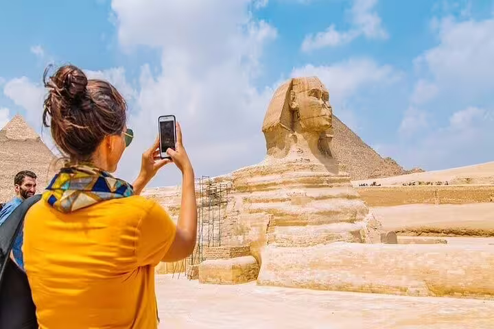 Traveler photographing the Great Sphinx and Giza Pyramids on a Cairo day tour by plane from Sharm El Sheikh