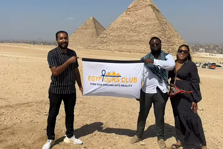 Guests and guide hold banner at Giza Pyramids viewpoint on private Cairo tour to pyramids, Sphinx and museum
