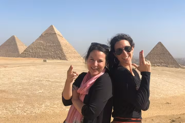 Happy travelers posing at Giza Pyramids on a private tour with camel ride and lunch in Cairo, Egypt