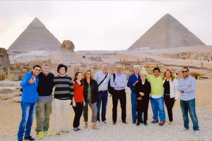 Tour group posing in front of the Great Pyramids and the Sphinx during a vibrant Egypt excursion.