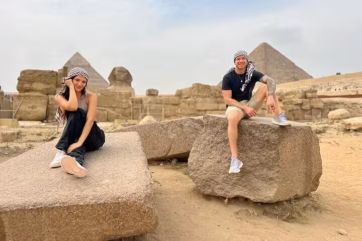 Travelers posing by ancient stones near the Giza Pyramids on a private tour, Cairo Egypt, desert sightseeing stop