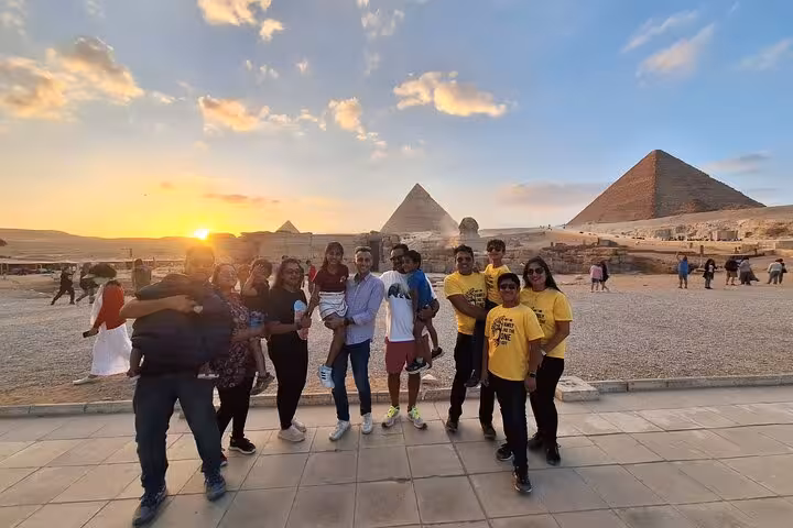 Group of tourists enjoy a sunset view at the Giza Pyramids, capturing the majestic scene in a memorable photo.