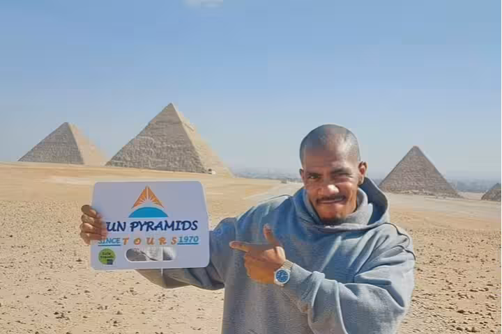 Tour guide at Giza Pyramids holding sign on Cairo day trip by air from Sharm El Sheikh with expert guide