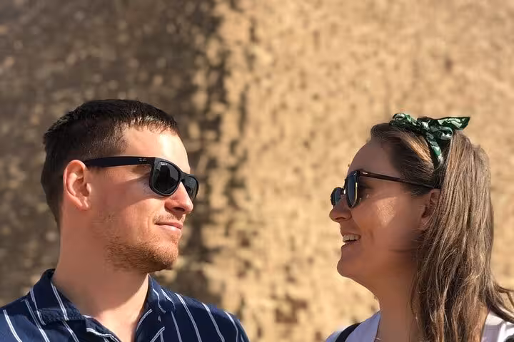 Tourists smiling near the Great Pyramid on an all inclusive Giza tour with pyramid entry, Sphinx and camel ride