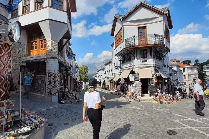 Tourist exploring the charming cobbled streets of Gjirokastër, Albania, surrounded by traditional Ottoman architecture.