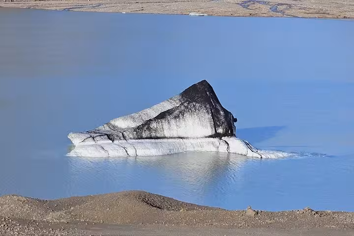 Dark sediment-covered iceberg floating in a glacial lagoon on Iceland's South Coast