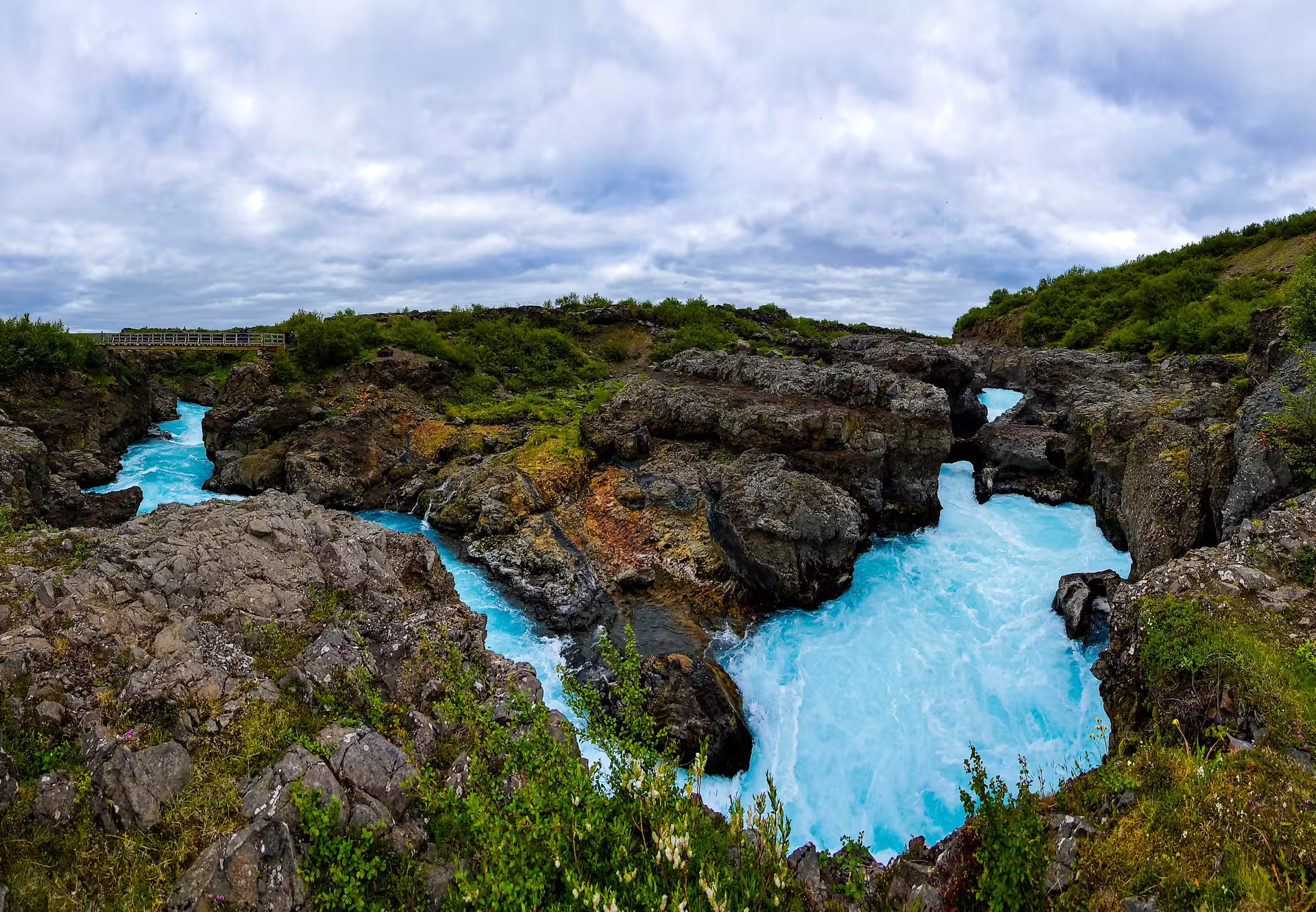 Stunning turquoise glacial river flowing through rugged lava rock canyon on Silver Circle private day tour in Borgarfjordur Iceland