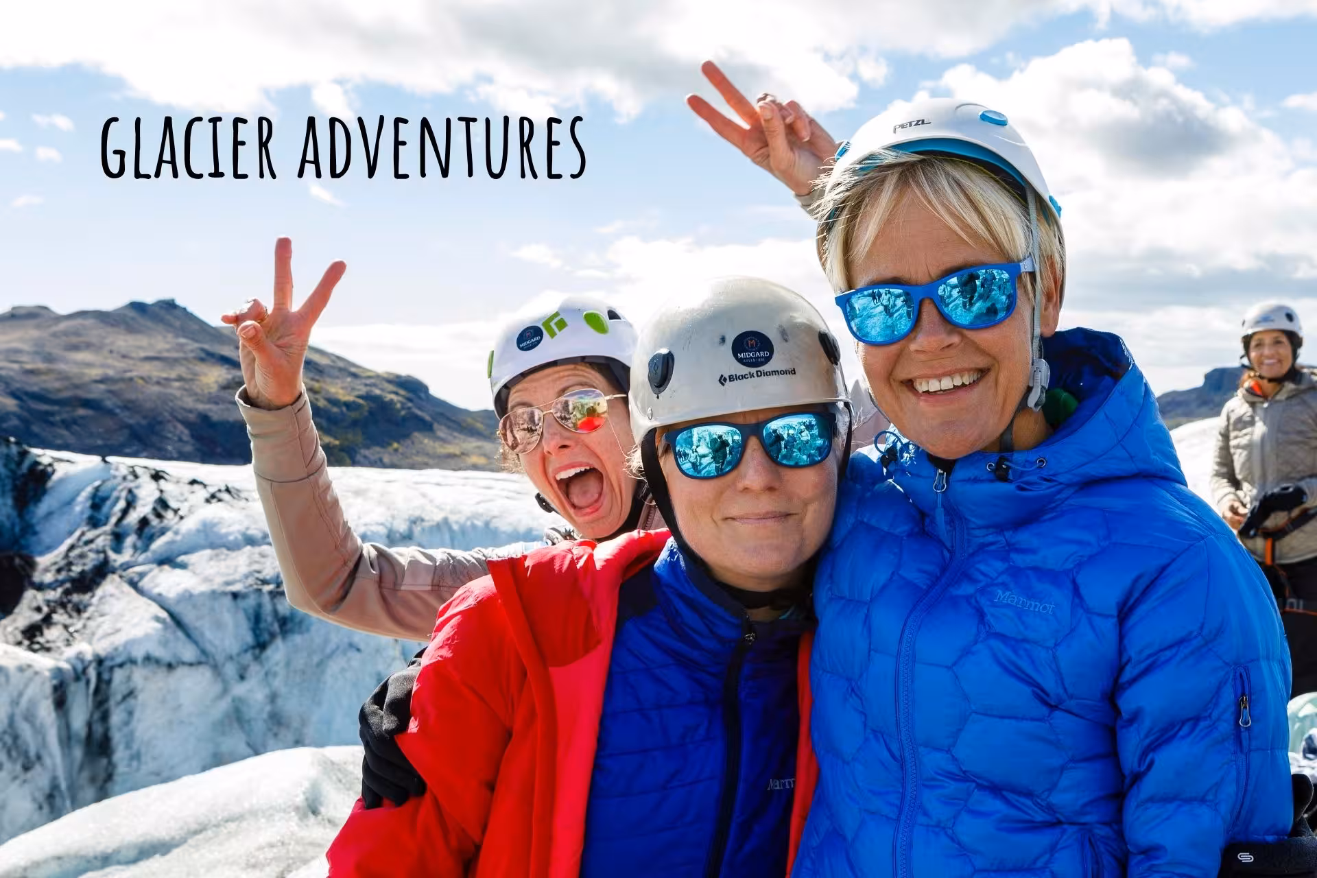 Three happy women in helmets and colorful jackets celebrating on a glacier in South Iceland