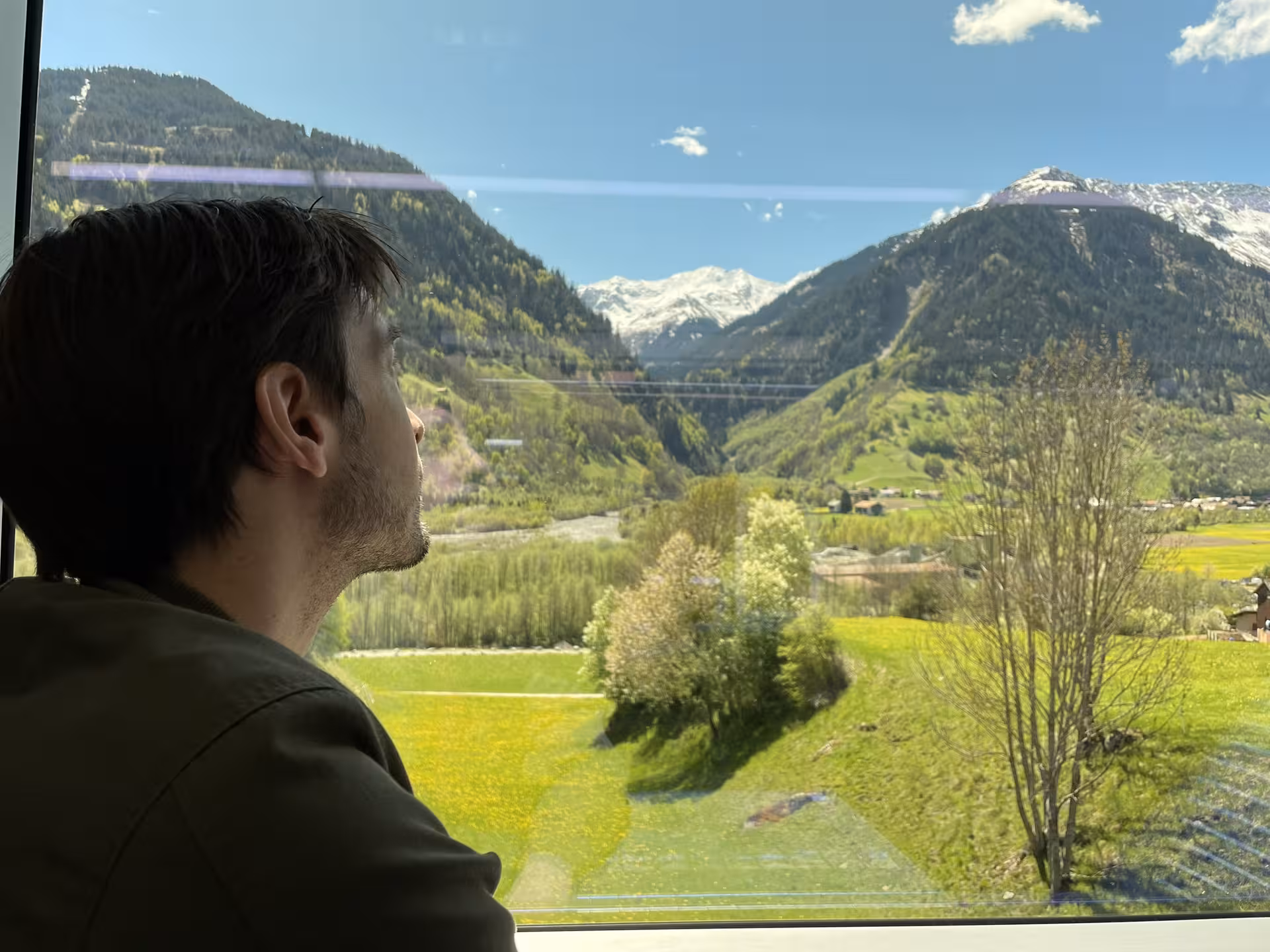 Traveler admiring Swiss Alps valleys from panoramic Glacier Express on premium Zurich route tour