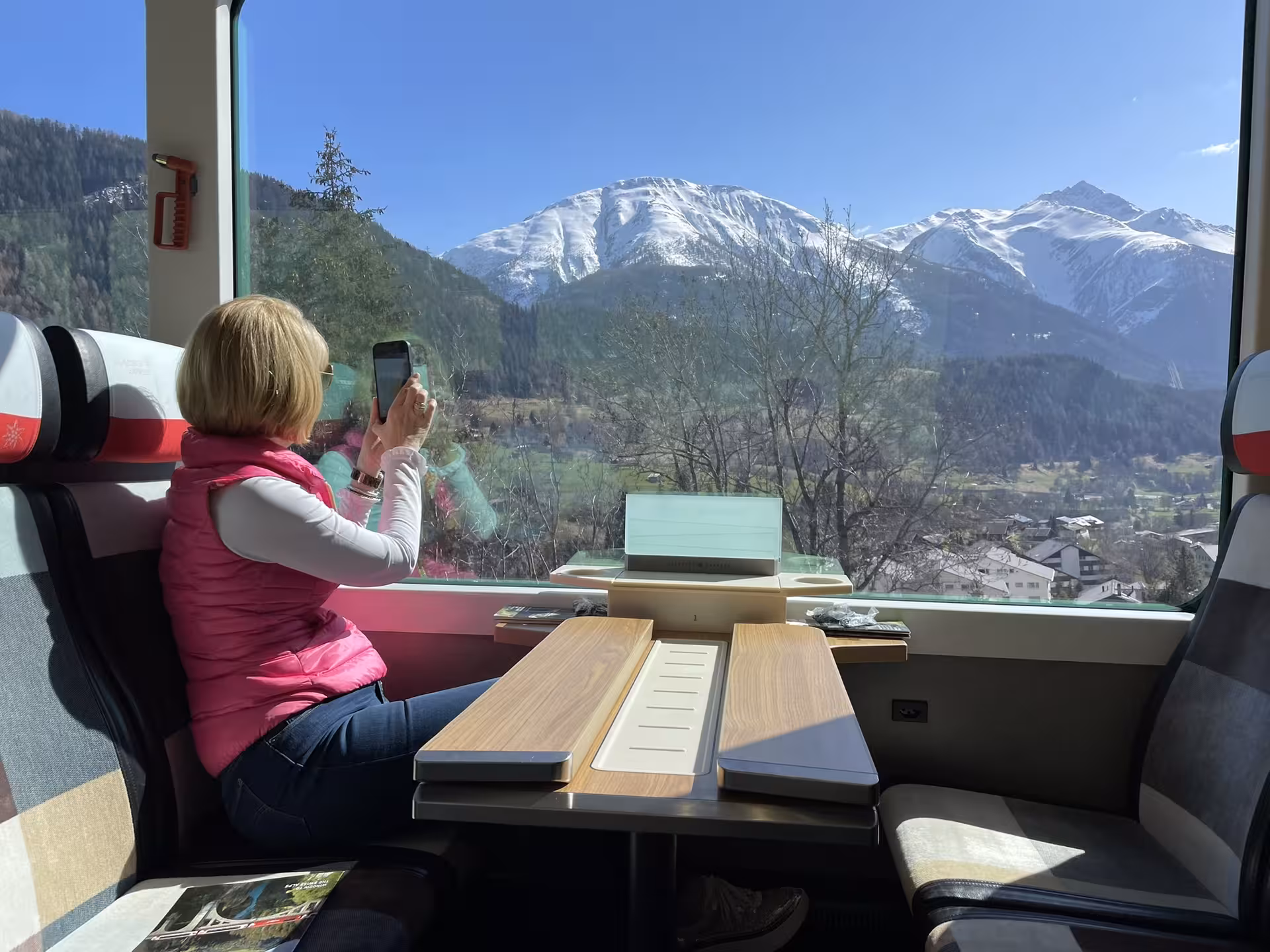 Passenger photographing snowy Swiss Alps from panoramic Glacier Express on a private Zurich route tour