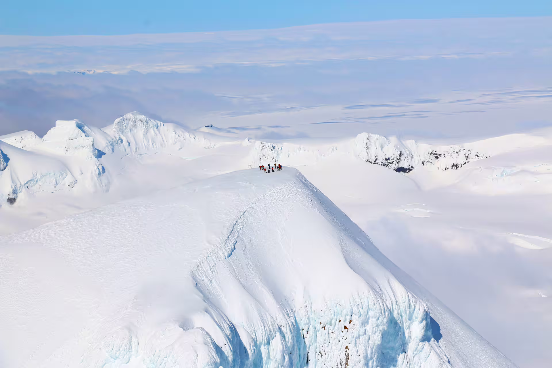 Small group of climbers on a snowy glacier ridge during a helicopter scenic landing in Skaftafell Iceland