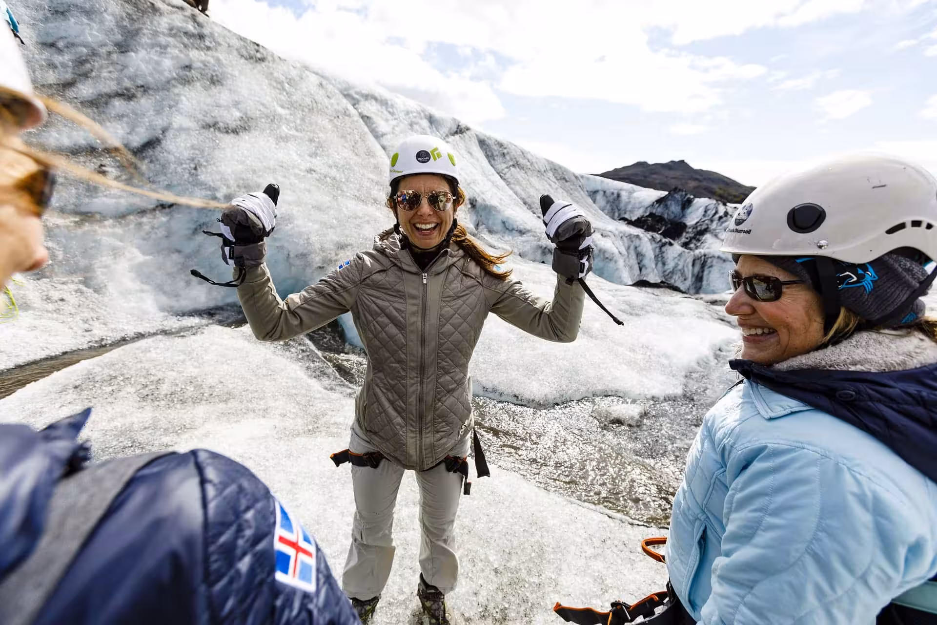 Excited woman in helmet and gloves celebrating on glacier during guided hike in Iceland