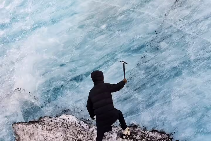Ice climber using ice axe on glacier face during Iceland glacier hike tour