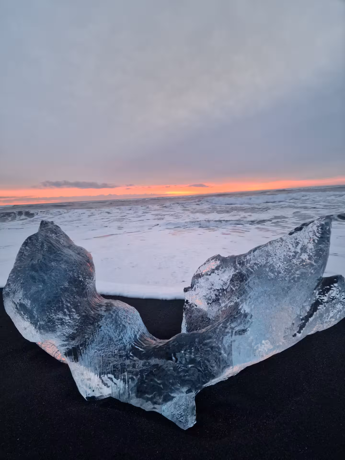 Glacial ice chunk on black sand beach at sunset in Southeast Iceland