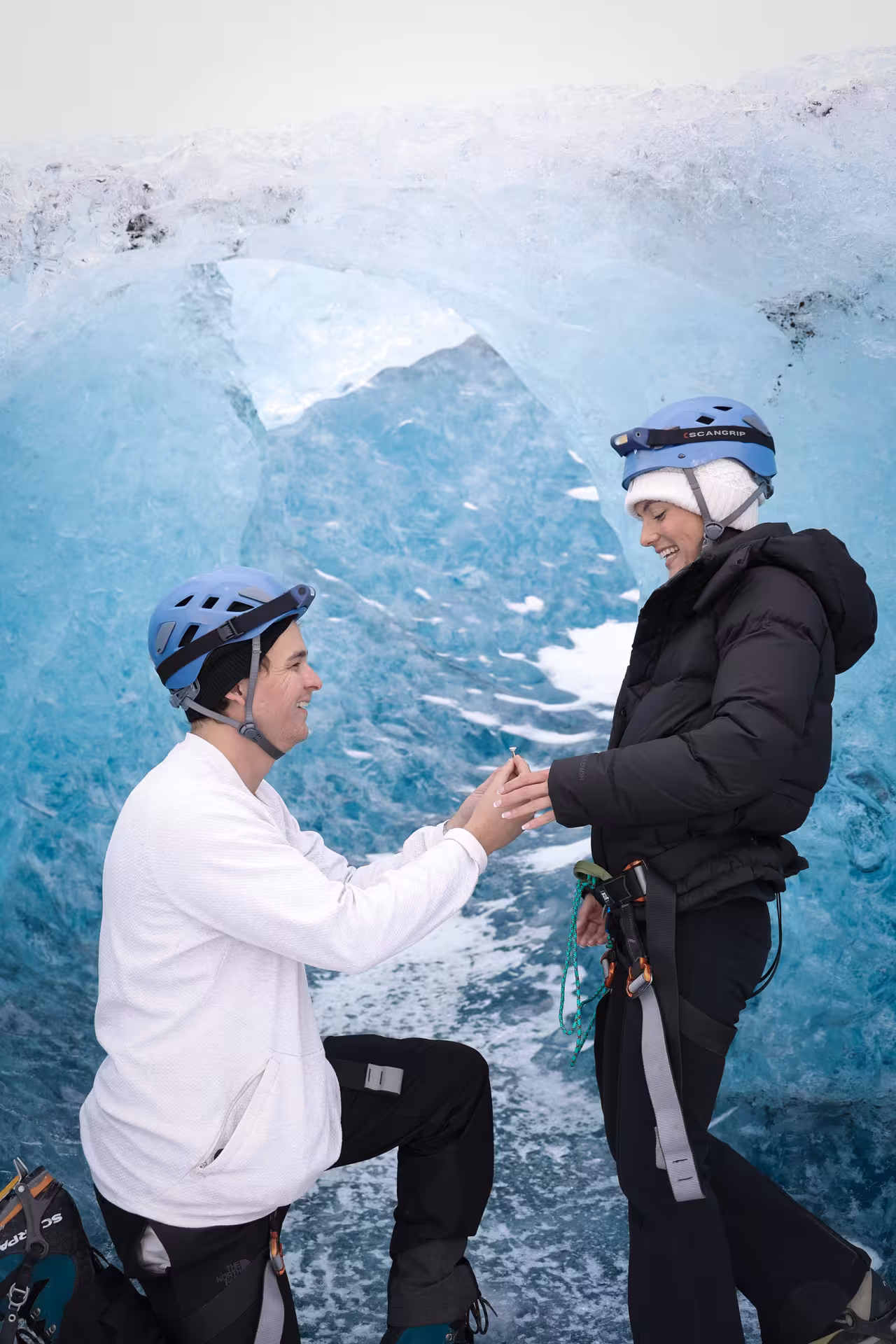 Romantic Iceland glacier proposal moment as man kneels with ring inside breathtaking blue ice cave on sunrise tour