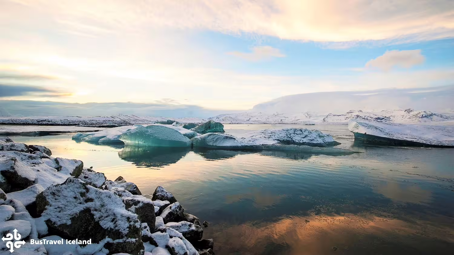 Turquoise icebergs floating on Jökulsárlón Glacier Lagoon with snow-covered mountains at sunset, Iceland