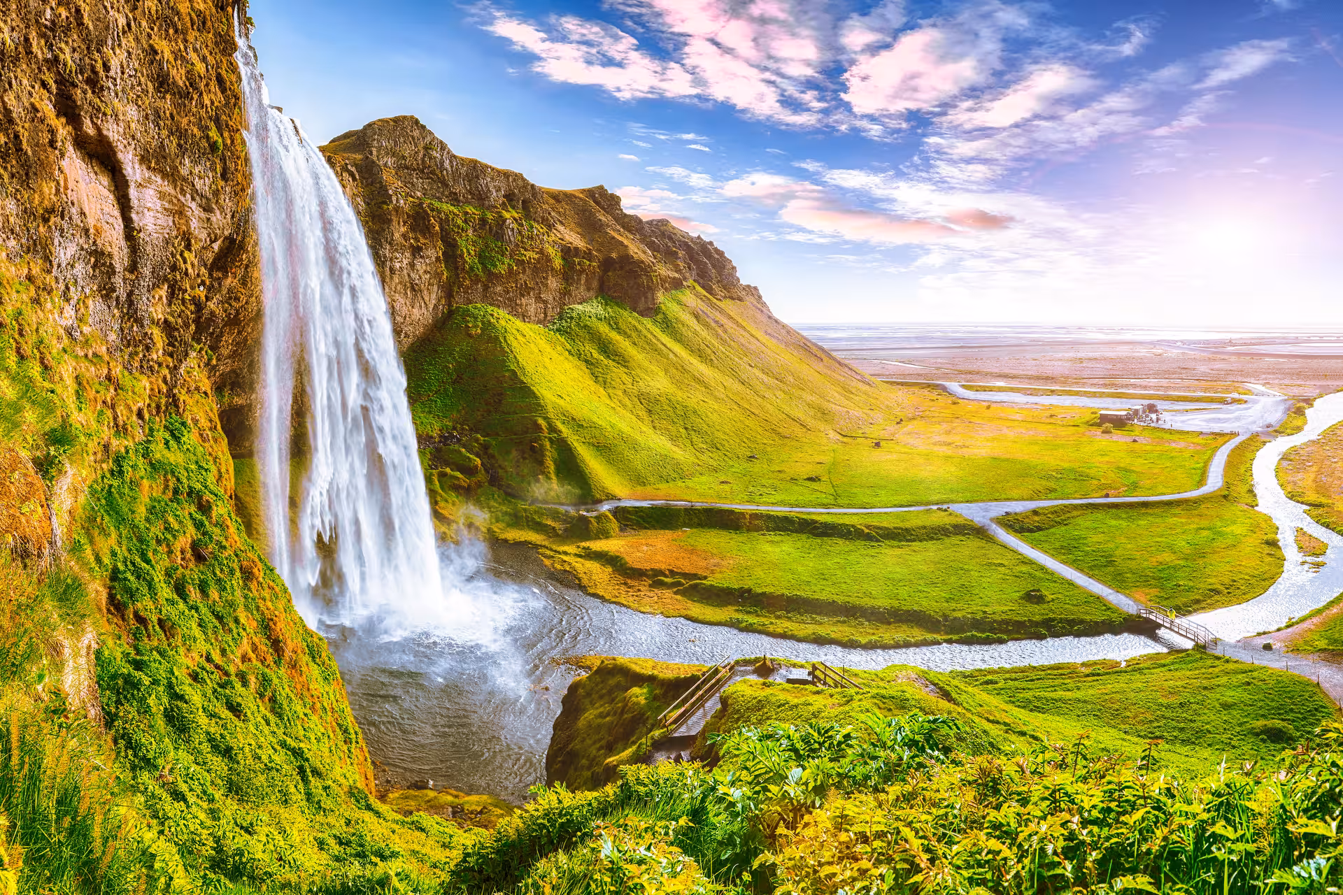 Breathtaking waterfall cascading down lush cliffs, offering scenic views on a private Glacier Lagoon & Diamond Beach tour.