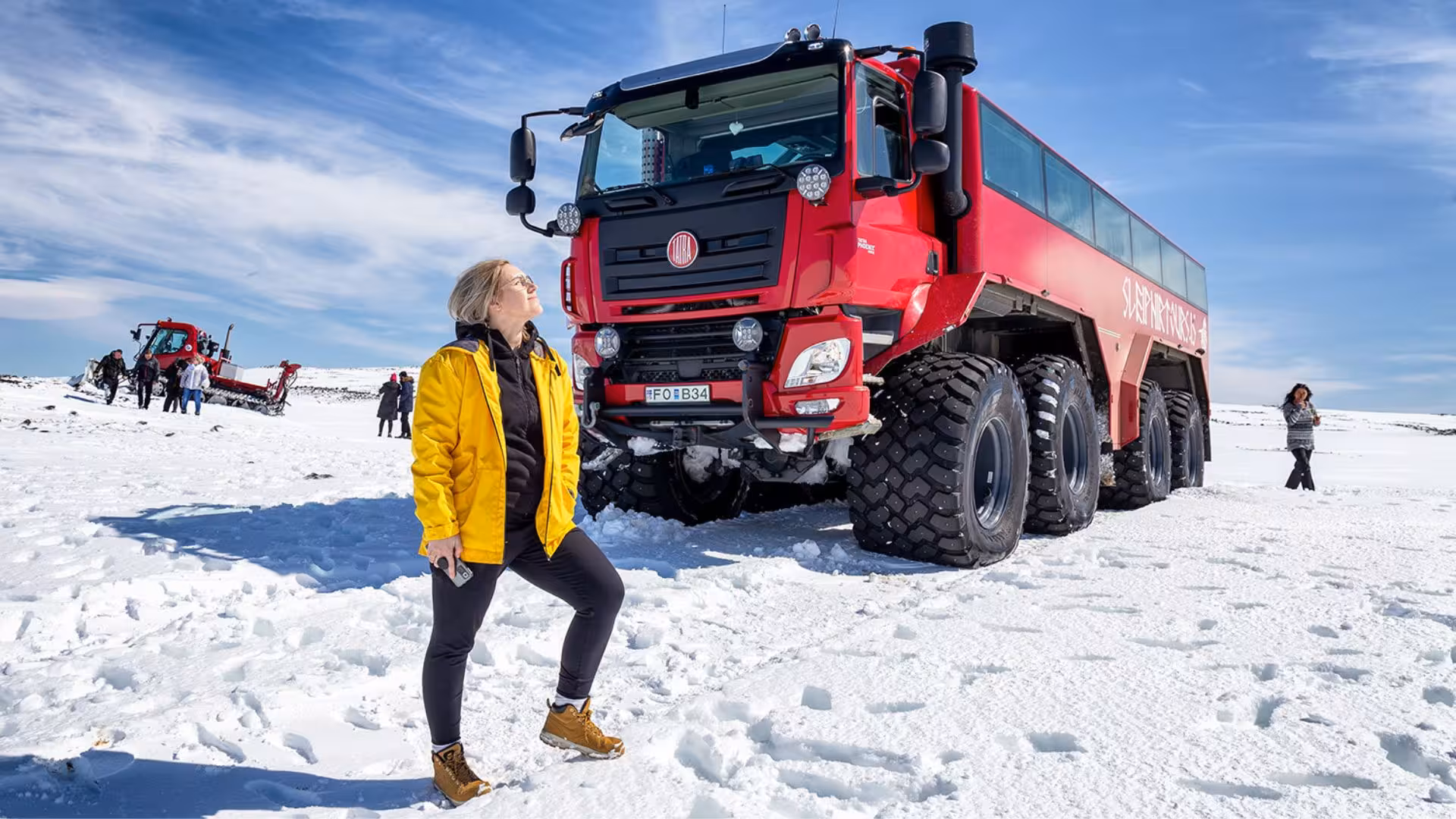 Traveler beside red Glacier Monster Truck on Iceland glacier, ice cave and glacier tour from Gullfoss