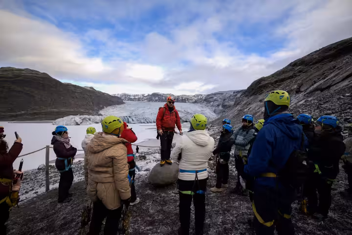 Tour guide briefing group of hikers wearing helmets at Solheimajokull glacier in Iceland