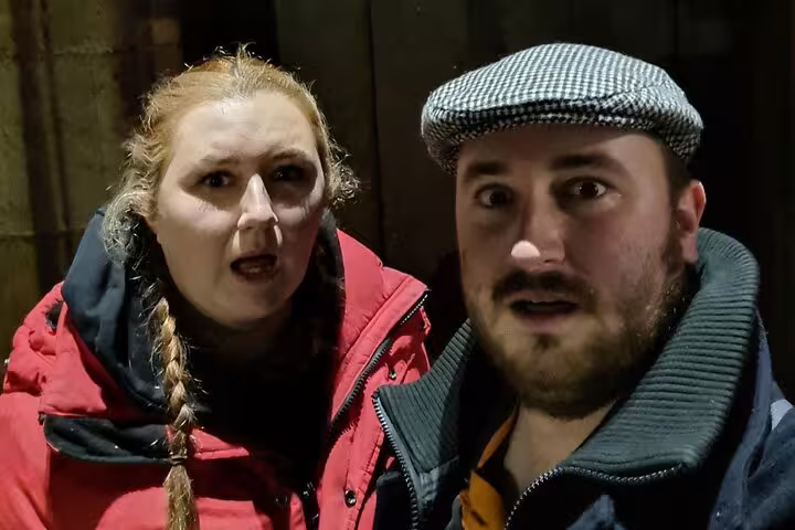 Two people with shocked expressions on Glasgow ghost walking tour at night