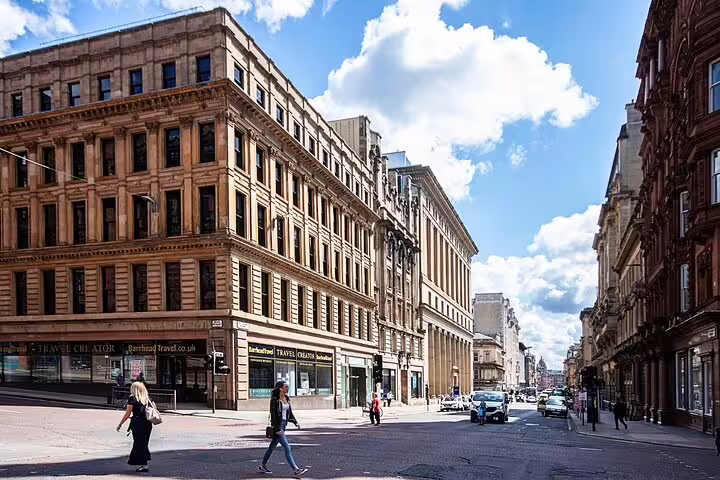 Historic sandstone buildings lining a Glasgow city centre street on a sunny day with pedestrians crossing
