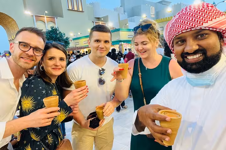 Global Village Dubai private tour guests enjoying traditional Arabic tea at evening market with pick up