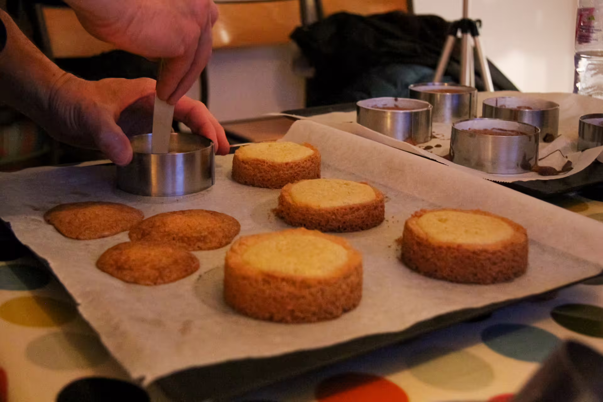 Hands cutting gluten-free sponge cake rounds with a metal ring mold during a Paris cooking class