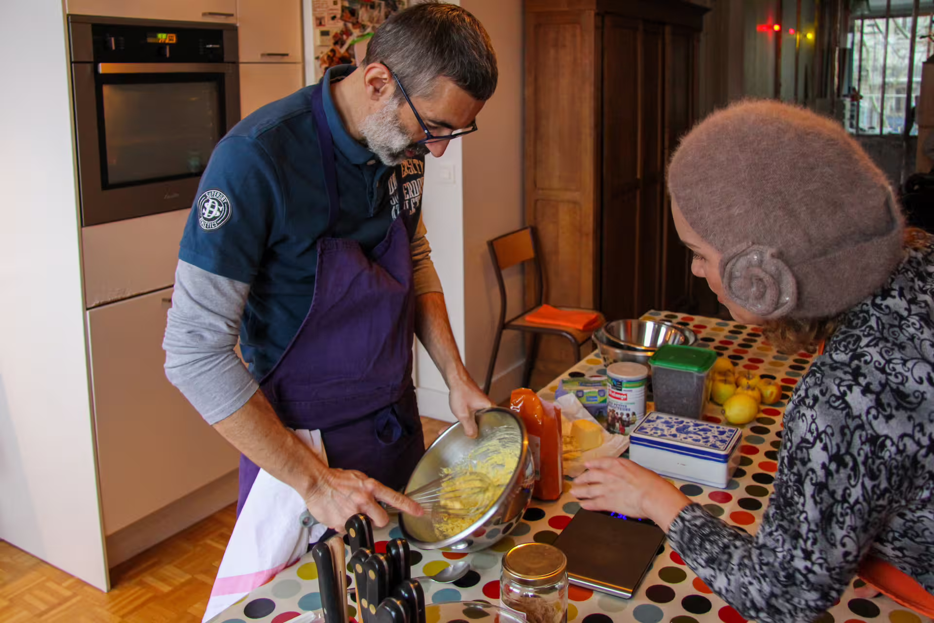 Man in apron mixing batter in silver bowl during gluten-free cooking class in Paris kitchen