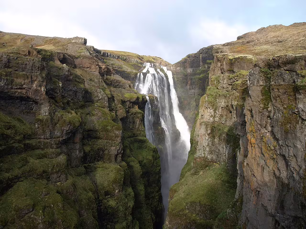 Glymur waterfall cascading down a narrow mossy canyon in Iceland