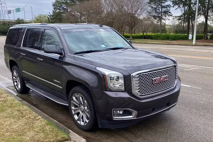 Dark gray GMC Yukon Denali XL SUV parked on wet pavement for private airport transfer
