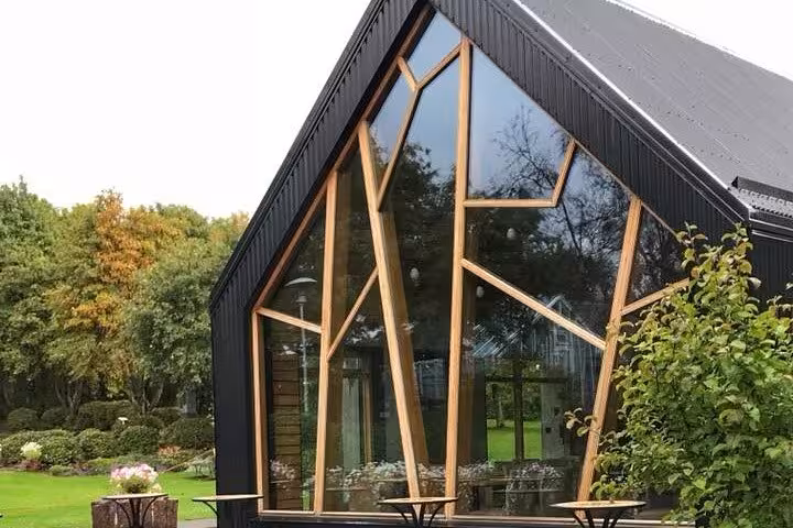 Modern architectural building with unique wooden window design surrounded by lush greenery in Akureyri.