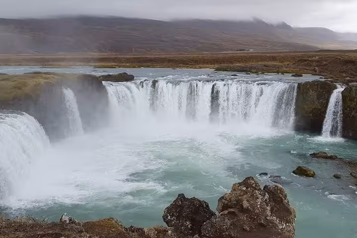 Majestic Godafoss waterfall with turquoise waters and rugged landscape, perfect for Akureyri shuttle round trip adventures.