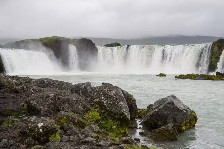 Godafoss waterfall with misty cascades and mossy rocks in North Iceland on a cloudy day