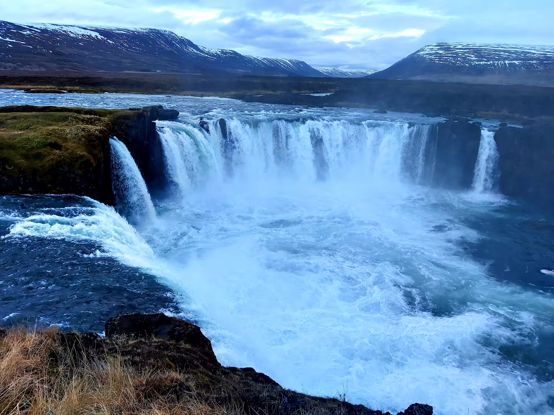 Godafoss waterfall horseshoe cascade with snow-capped mountains in North Iceland