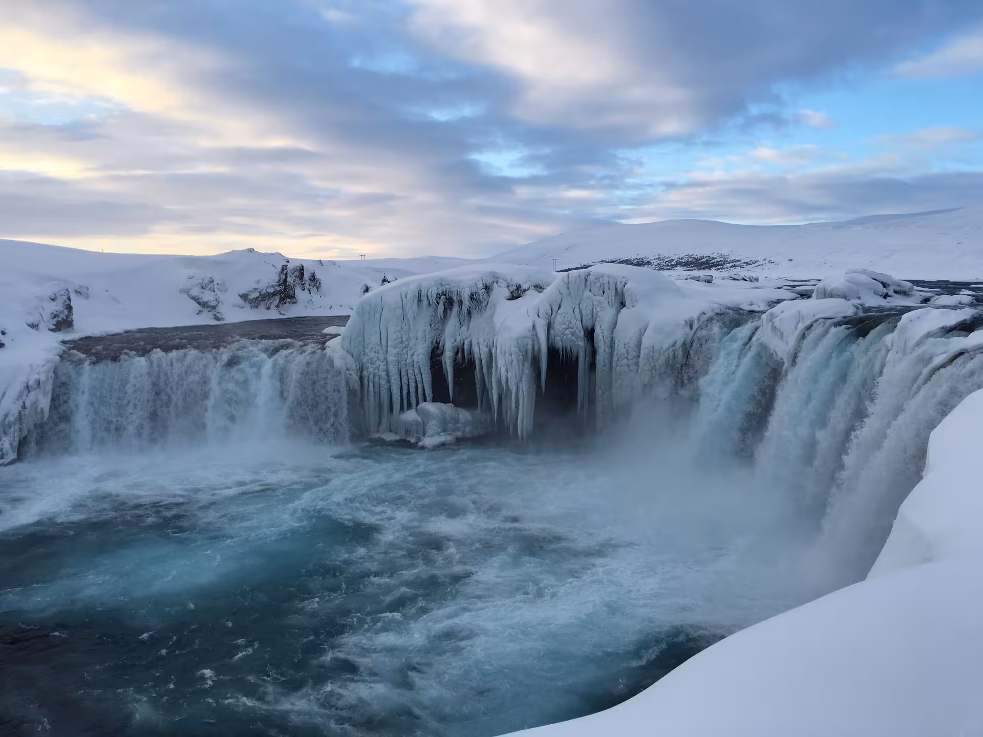 Stunning view of the frozen Godafoss waterfall surrounded by snow, featured in the Private Lake Myvatn Day Tour.