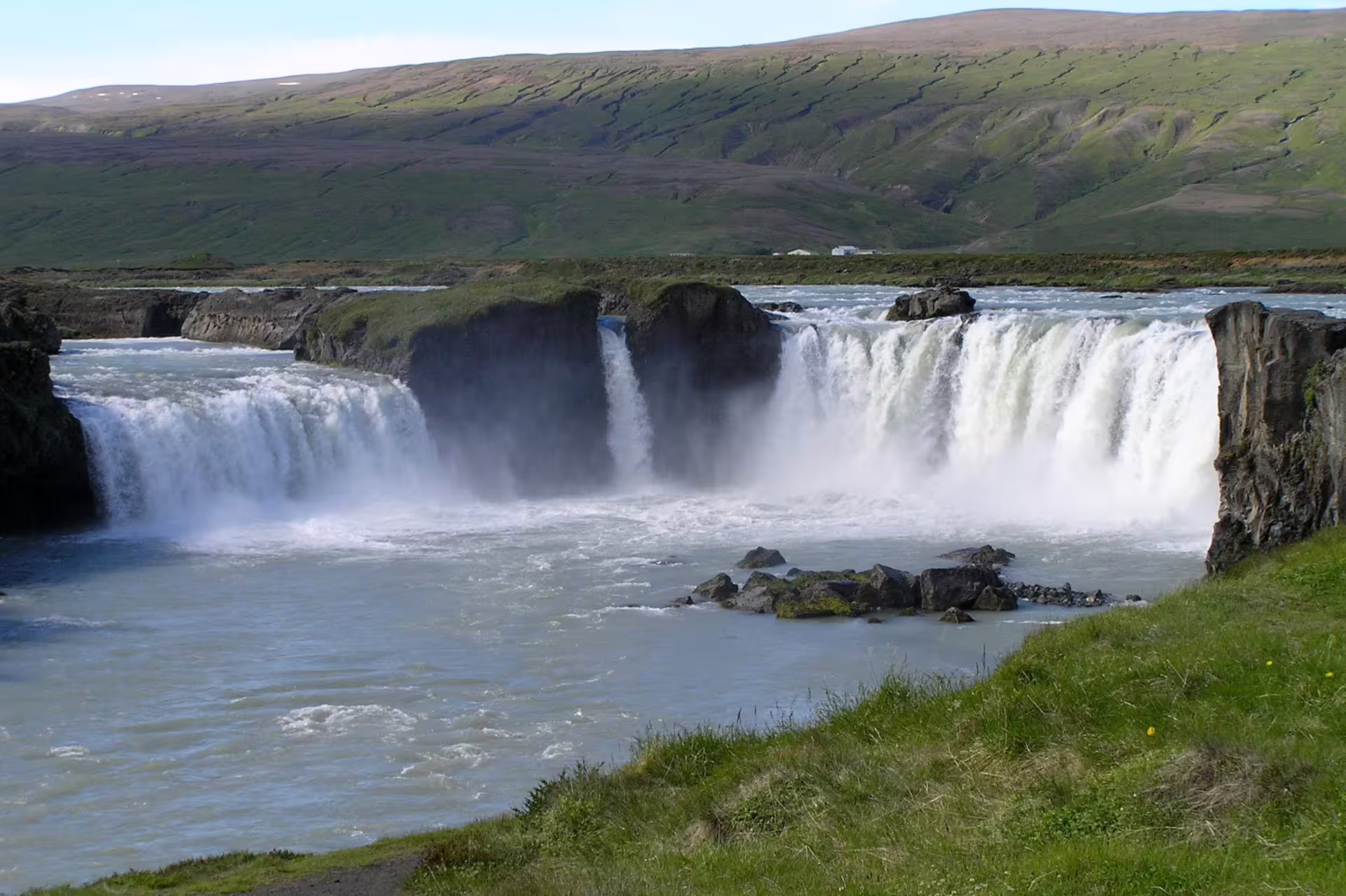 Godafoss waterfall cascading over wide basalt cliffs into a turquoise river in Iceland