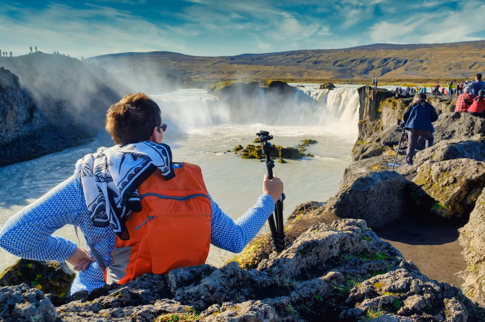 Traveler with camera enjoys Godafoss waterfall's majestic beauty, a highlight of Iceland's 5-day scenic journey.