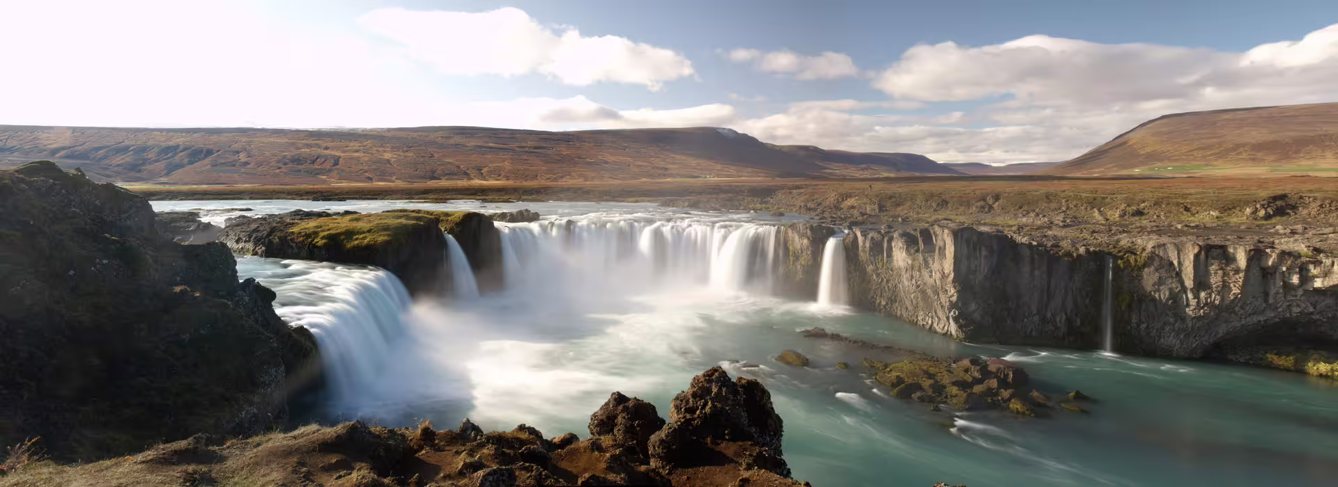 Godafoss waterfall cascading over basalt cliffs into turquoise glacial river, Iceland