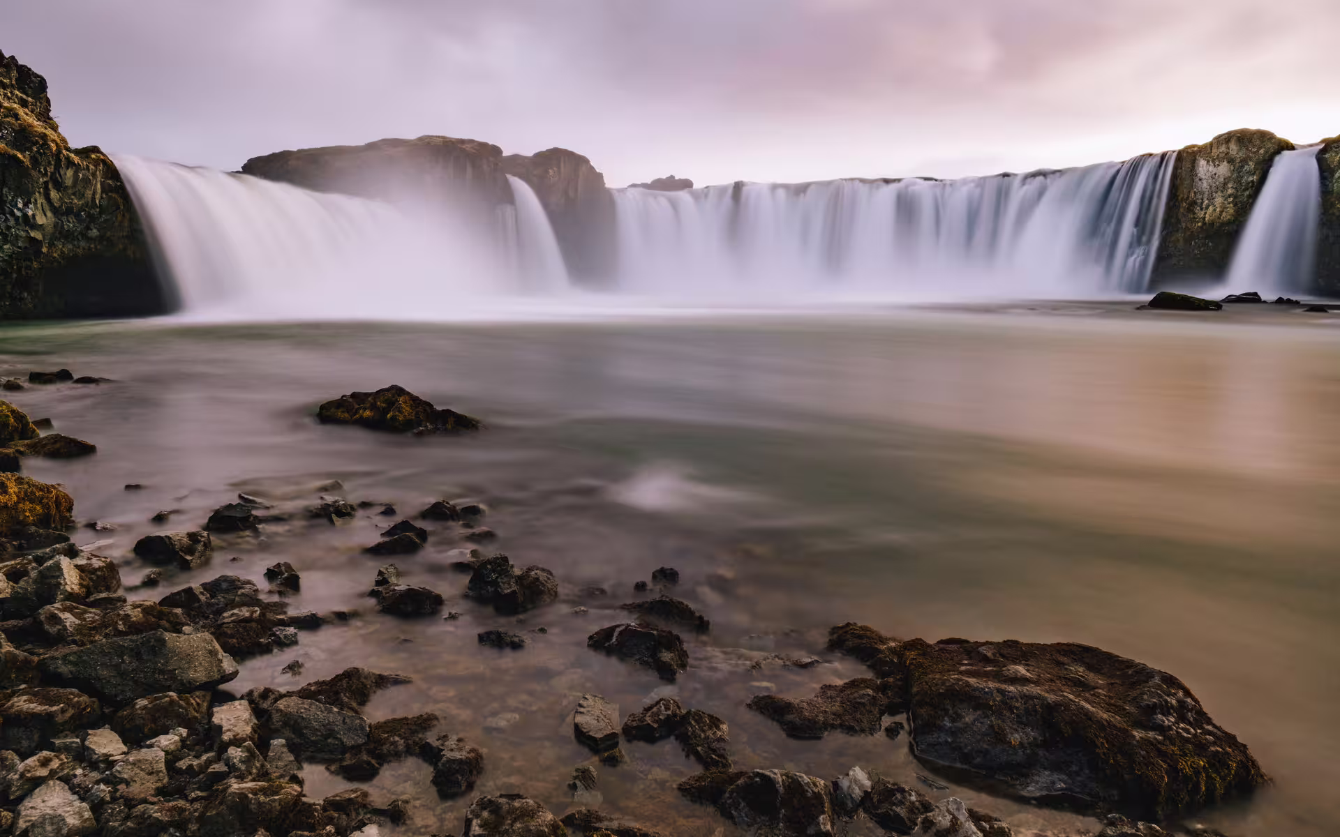 Godafoss waterfall cascading over rocky cliffs into a misty pool in Akureyri, Iceland