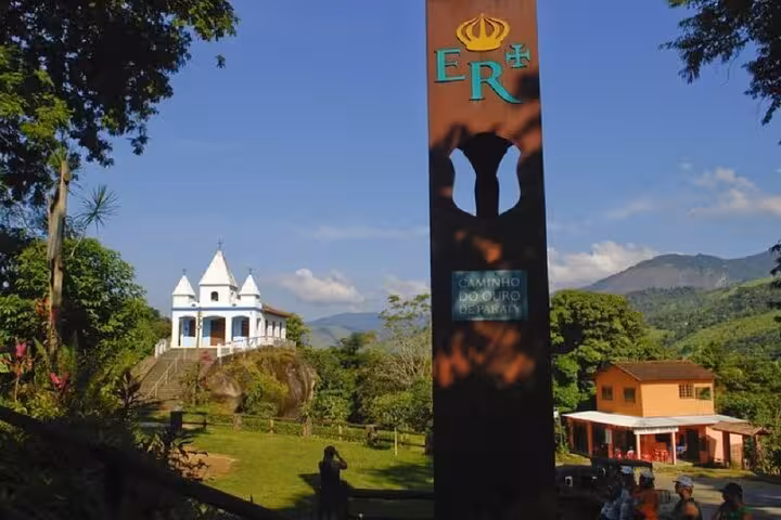 Caminho do Ouro monument with a historic chapel in the background, showcasing Paraty's cultural hiking experience.