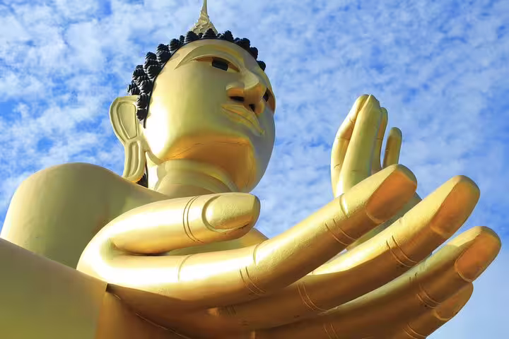 Golden Buddha statue with hands raised against blue sky in Bangkok old town