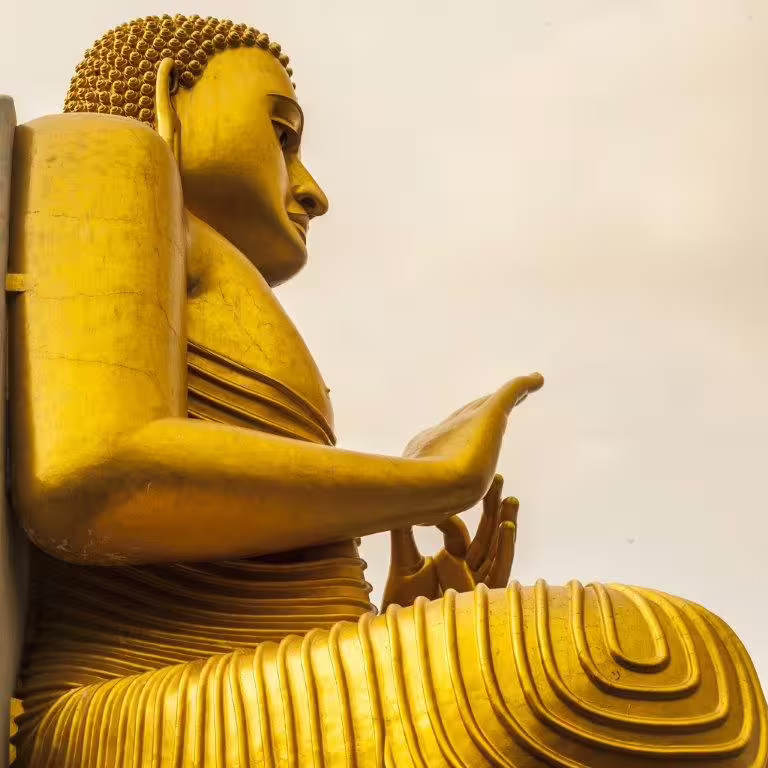 Majestic golden Buddha statue in Sri Lanka showcasing intricate details against a tranquil sky, a must-see cultural landmark.