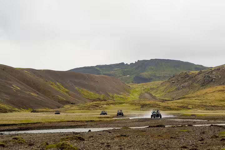 Buggy vehicles crossing a shallow river in an Icelandic highland valley near Reykjavik