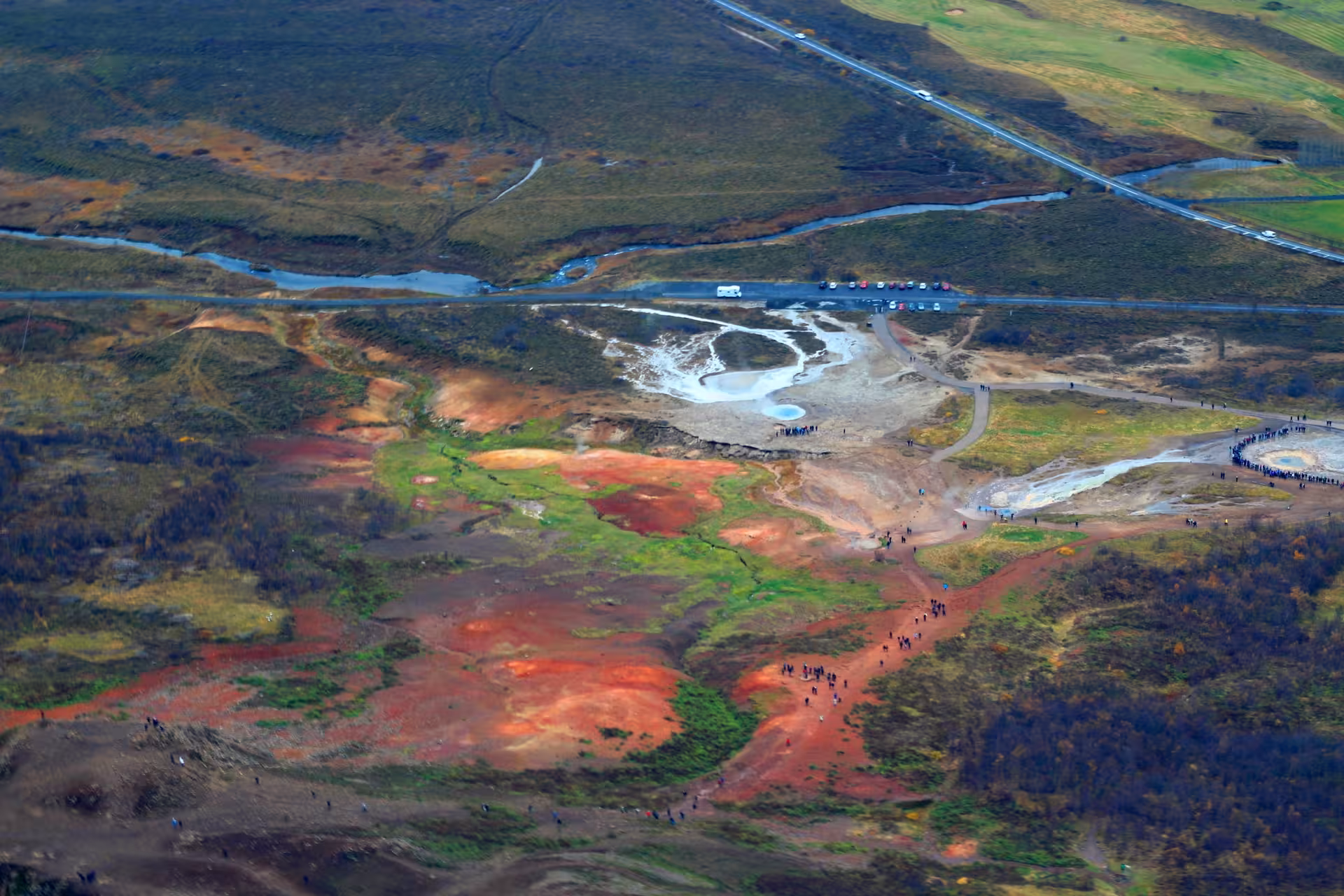 Aerial view of Iceland's Golden Circle geothermal area with colorful red and green terrain and tourists on paths